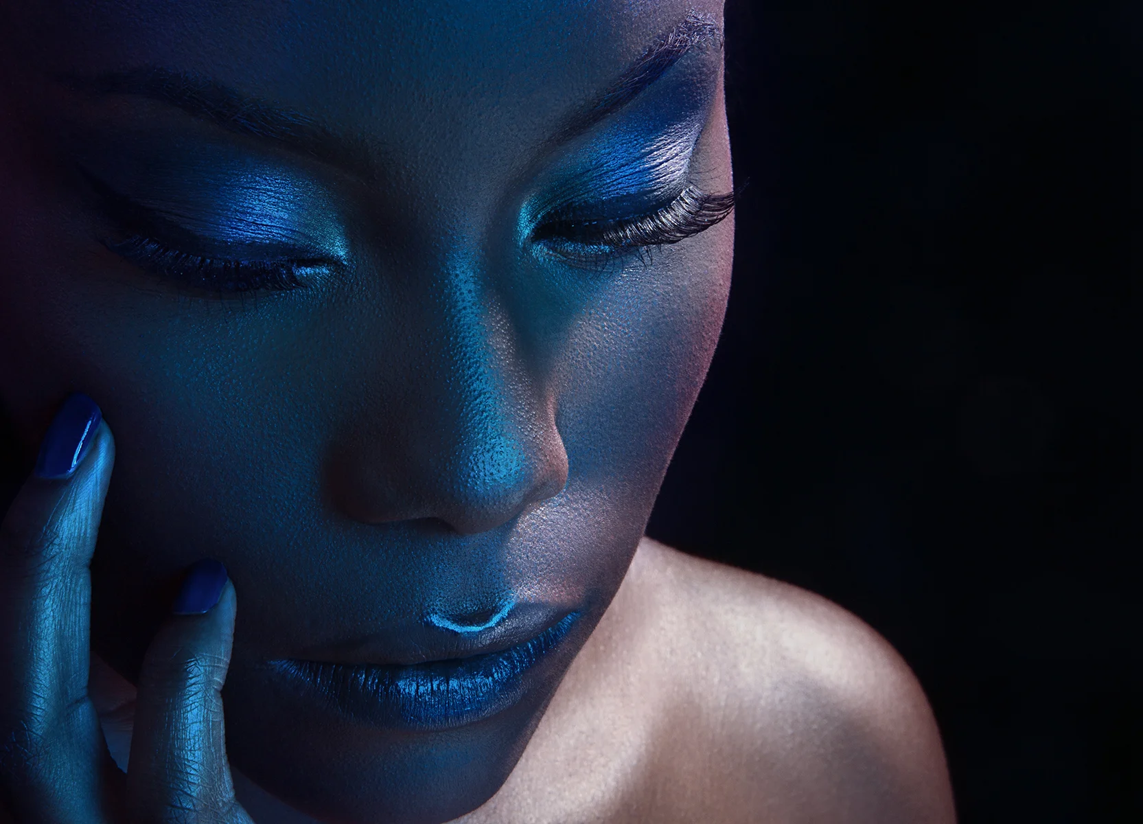 Dramatic beauty portrait retouching featuring a Black model with metallic blue eyeshadow and blue lipstick under moody lighting